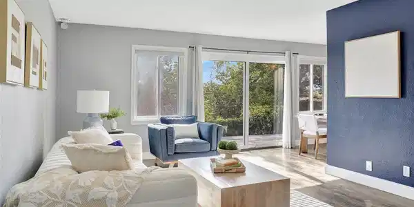Image 4: Light-filled living room featuring expansive windows, durable flooring, and an open flow into the dining area.