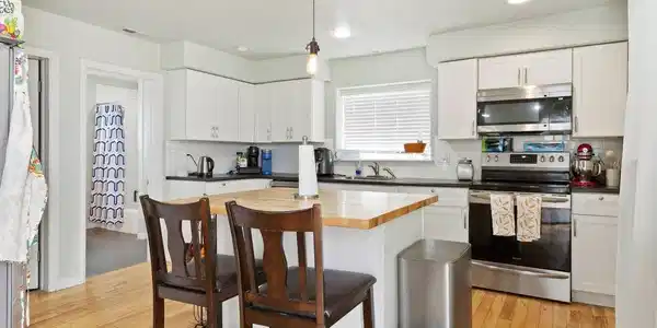Image 2: The kitchen showcases whitewashed cabinetry, upgraded appliances, subway tile backsplash, and a large butcher block island with seating. Image 2: The kitchen showcases whitewashed cabinetry, upgraded appliances, subway tile backsplash, and a large butcher block island with seating.