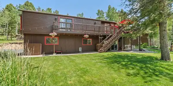 Image 2: From the wraparound upper deck to the classic wood-and-red-trim exterior, this home wears its mountain character with pride. Surrounded by open lawn and mature pines, it's the kind of setting that turns every day into a getaway. Image 2: From the wraparound upper deck to the classic wood-and-red-trim exterior, this home wears its mountain character with pride. Surrounded by open lawn and mature pines, it's the kind of setting that turns every day into a getaway.