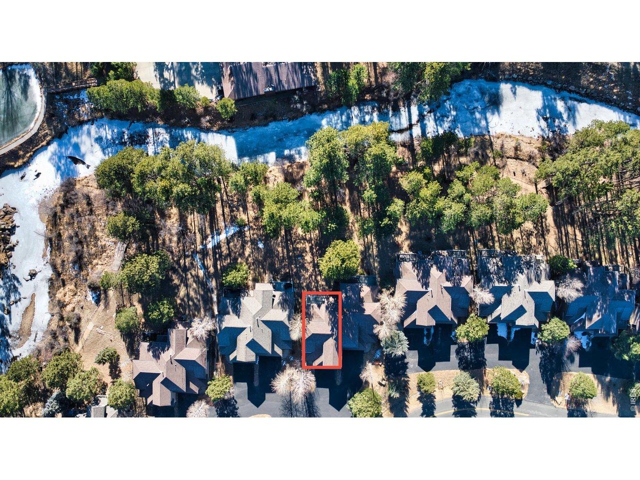 Image 4: Overhead view highlighting the property within the Riverfront townhome community. Shows private setting backing to natural open space with trees and riverfront access.