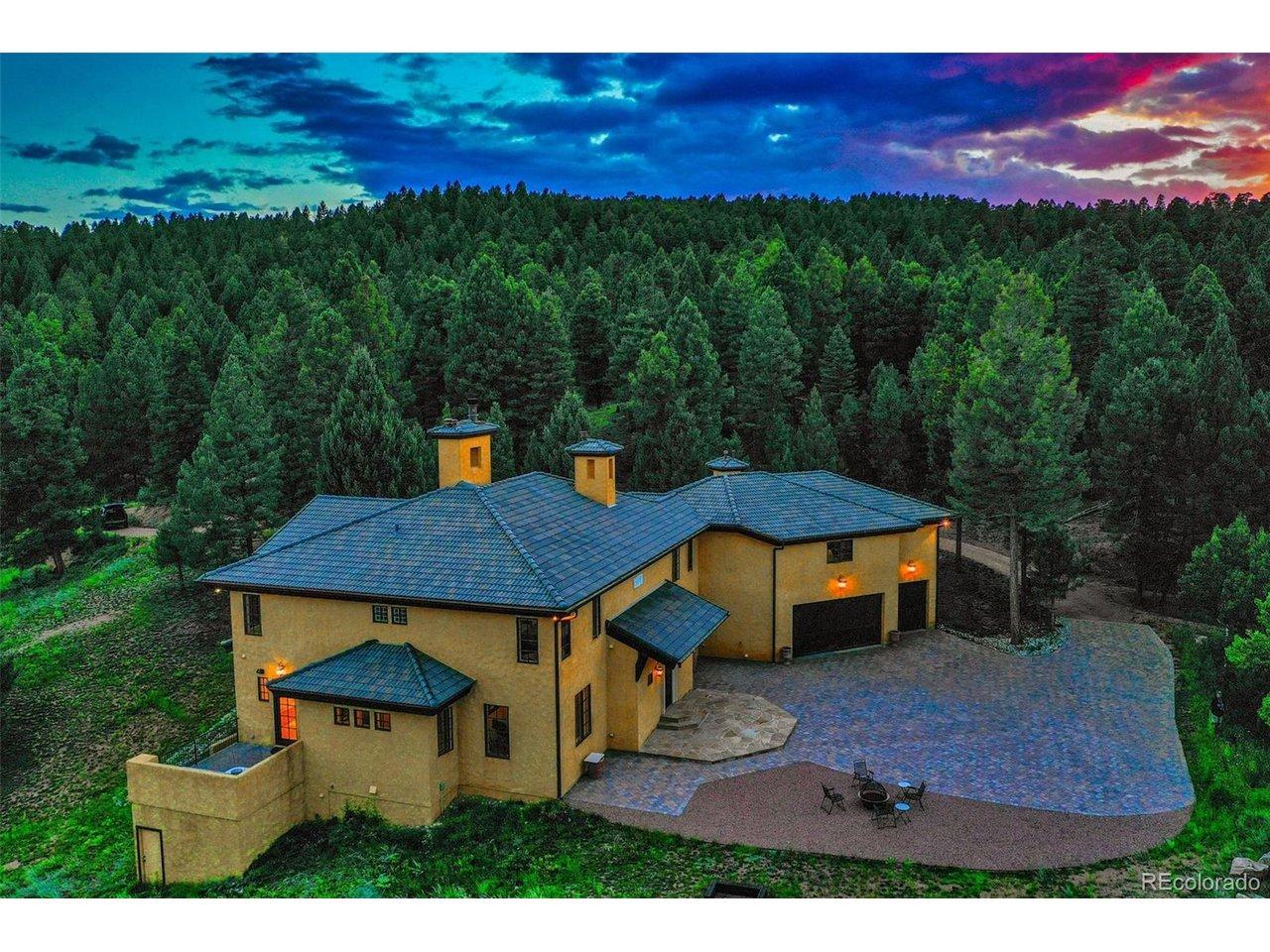 Image 1: Aerial view at dusk of the structure and front of the home with the paver driveway platform. The Home is located in the eastern rear corner of the 40 acre parcel preserving the natural forest. The north and west boundaries of the property are adjacent to n
