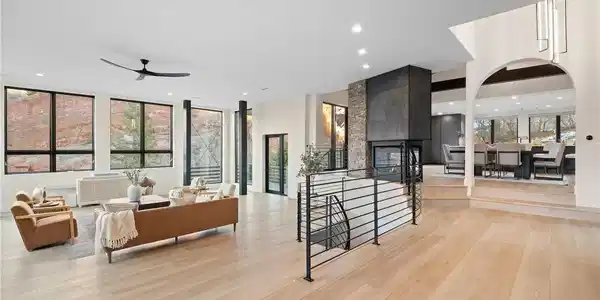 Image 2: Open concept main living area with fireplace, hardwood floors, and walls of windows framing the formations