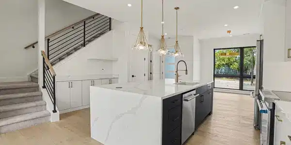 Image 4: The spacious kitchen island creates a natural gathering place, complemented by waterfall-edge quartz, custom cabinetry & designer lighting.