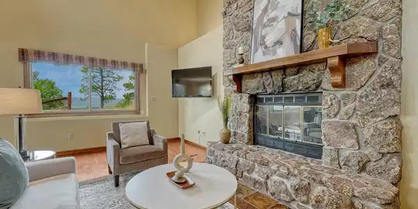 Image 4: Spacious family room with LVP flooring, vaulted ceilings, and a floor-to-ceiling stone fireplace with raised hearth and wood-burning insert. Image 4: Spacious family room with LVP flooring, vaulted ceilings, and a floor-to-ceiling stone fireplace with raised hearth and wood-burning insert.