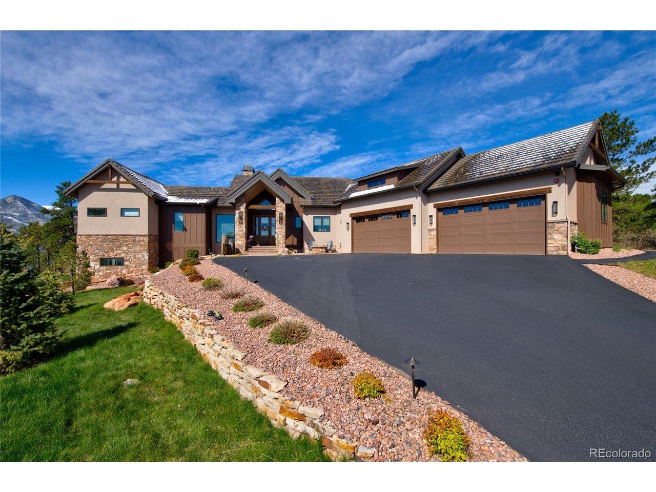 Image 2: Built for Colorado living. Expansive side elevation featuring a 4-car attached garage with custom carriage-style doors, mixed stone and stucco facade, multilevel landscaping, and direct mountain views from the driveway. Image 2: Built for Colorado living. Expansive side elevation featuring a 4-car attached garage with custom carriage-style doors, mixed stone and stucco facade, multilevel landscaping, and direct mountain views from the driveway.