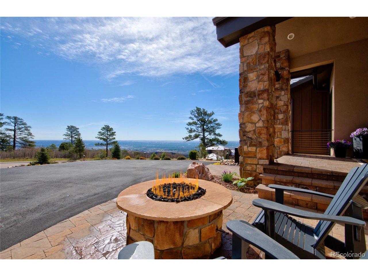 Image 4: The view starts the moment you arrive. Front entry patio featuring a custom stone gas fire pit, Adirondack seating, and sweeping panoramic views of Colorado Springs and the eastern plains stretching to the horizon. Image 4: The view starts the moment you arrive. Front entry patio featuring a custom stone gas fire pit, Adirondack seating, and sweeping panoramic views of Colorado Springs and the eastern plains stretching to the horizon.