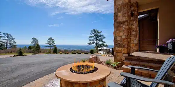 Image 4: The view starts the moment you arrive. Front entry patio featuring a custom stone gas fire pit, Adirondack seating, and sweeping panoramic views of Colorado Springs and the eastern plains stretching to the horizon.