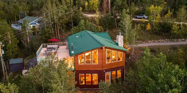 Image 2: As evening settles in, this home glows against its peaceful mountain surroundings