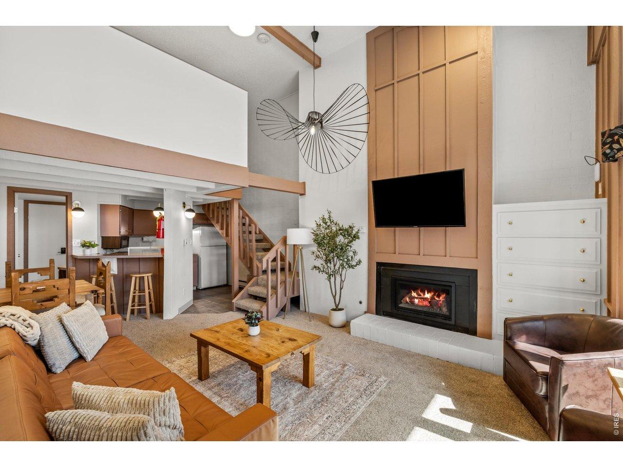 Image 1: Vaulted ceilings and a cozy fireplace make this living room the heart of the home. Relax on the leather sofa, stream your favorite shows, or gather after a day on the mountain. The open layout flows seamlessly to the kitchen and dining area.