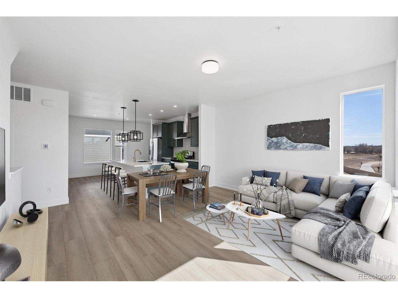 Image 1: Bright and open main living area featuring wide-plank flooring, expansive windows, and seamless flow between the living, dining, and kitchen spaces. Virtually Staged.