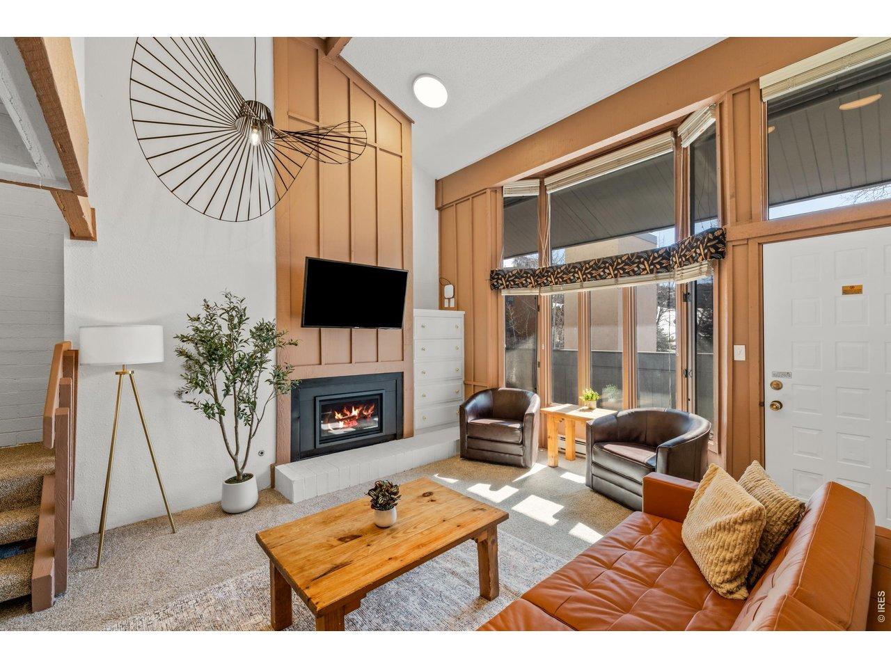 Image 2: Bright, sun-filled living room with soaring windows and a cozy fireplace. Comfortable seating makes it the perfect spot for morning coffee or relaxing after a day on the slopes.