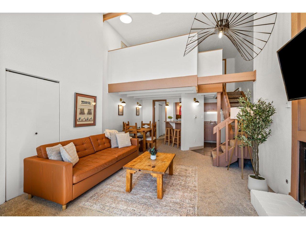 Image 4: Bright and open living room with soaring vaulted ceilings and a cozy lounge area. The loft above adds a fun mountain-cabin feel, while the open layout connects seamlessly to the kitchen and dining space.