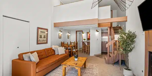 Image 4: Bright and open living room with soaring vaulted ceilings and a cozy lounge area. The loft above adds a fun mountain-cabin feel, while the open layout connects seamlessly to the kitchen and dining space. Image 4: Bright and open living room with soaring vaulted ceilings and a cozy lounge area. The loft above adds a fun mountain-cabin feel, while the open layout connects seamlessly to the kitchen and dining space.