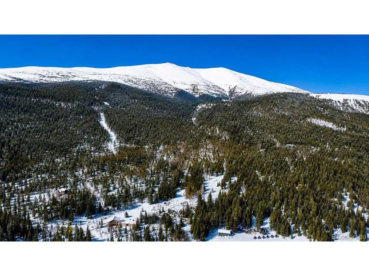 Image 1: Private ski run cuts through 47 acres of alpine forest with a massive snow-capped peak behind it. Your mountain, your run. Image 1: Private ski run cuts through 47 acres of alpine forest with a massive snow-capped peak behind it. Your mountain, your run.
