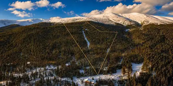 Image 4: Aerial view of Alma Ski Area at golden hour, with property boundaries highlighted. The cleared ski run bisecting the parcel is clearly visible, showcasing the north-facing terrain, dense pine forest, and the dramatic backdrop of the Mosquito Range above. Image 4: Aerial view of Alma Ski Area at golden hour, with property boundaries highlighted. The cleared ski run bisecting the parcel is clearly visible, showcasing the north-facing terrain, dense pine forest, and the dramatic backdrop of the Mosquito Range above.
