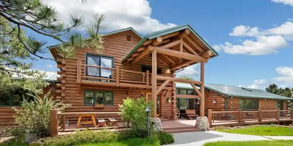 Image 2: Freshly painted logs, composite decking, metal roofing, 3+ Car attached garage and multiple barns, sheds, equipment storage buildings. Domestic Well, septic, small junior water right