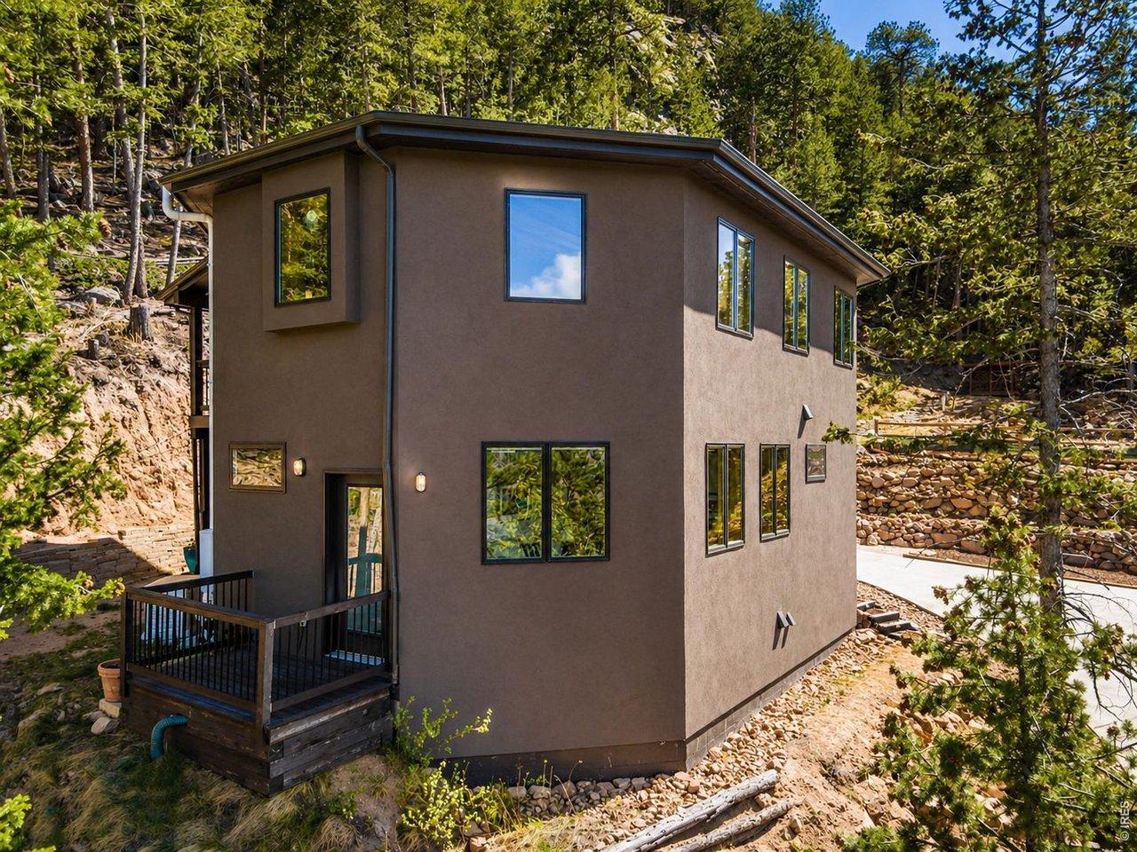 Image 4: Modern mountain exterior with natural rock landscaping, private deck access, and surrounding pine trees. Image 4: Modern mountain exterior with natural rock landscaping, private deck access, and surrounding pine trees.