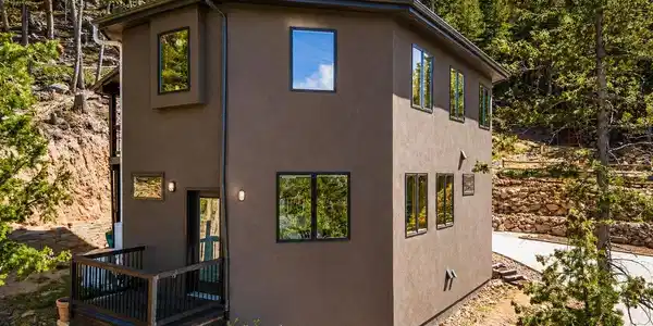 Image 4: Modern mountain exterior with natural rock landscaping, private deck access, and surrounding pine trees. Image 4: Modern mountain exterior with natural rock landscaping, private deck access, and surrounding pine trees.