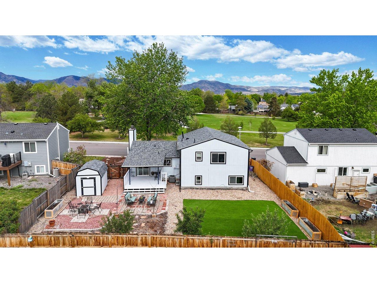 Image 3: Fully landscaped backyard with covered porch, two patios, turf play/lounge area, xeriscaping, fruit trees, and two storage sheds
