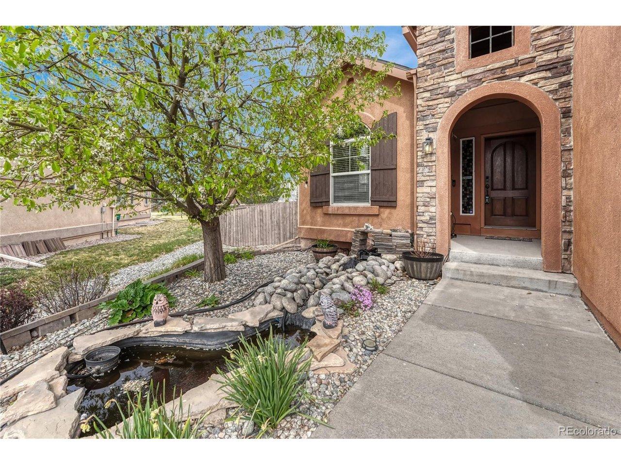 Image 2: A soothing rock waterfall and fish pond greet you at the covered entryway, creating a serene and welcoming transition into the home