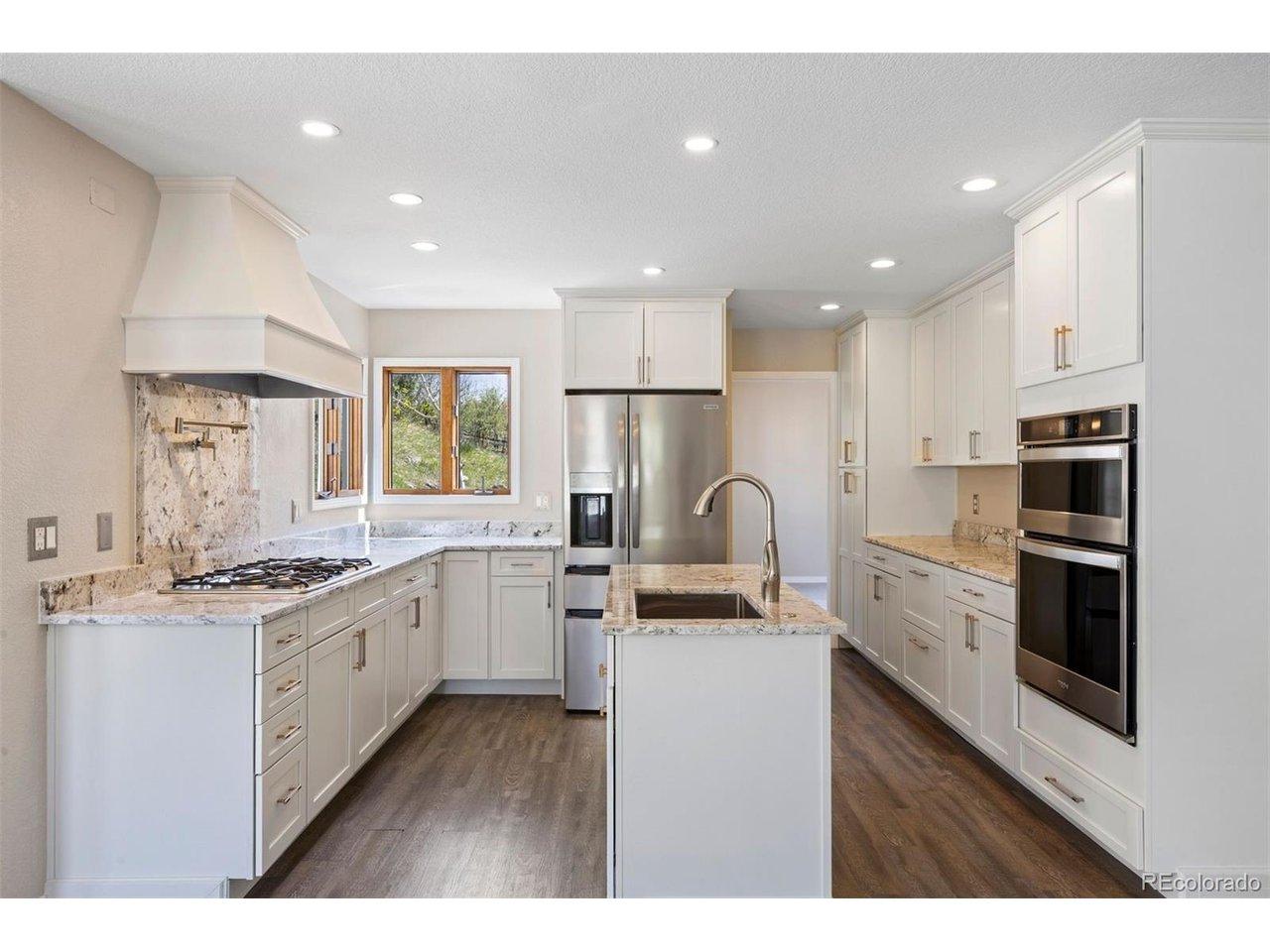 Image 4: Beautifully updated kitchen featuring white cabinetry, granite countertops, five-burner gas cooktop with pot-filler, and stainless steel appliances.