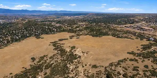 Image 4: Panoramic aerial with snow-dusted mountains beyond. The broad meadow sits minutes from town amenities yet retains an open-range character increasingly hard to find. Image 4: Panoramic aerial with snow-dusted mountains beyond. The broad meadow sits minutes from town amenities yet retains an open-range character increasingly hard to find.