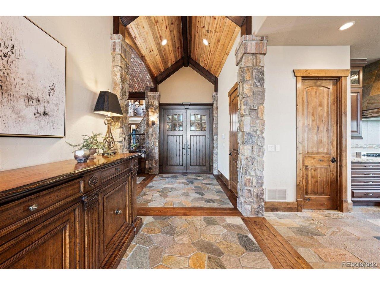Image 4: Step inside the grand foyer to discover an open concept layout accented by natural stone, wood beams, and custom features. Image 4: Step inside the grand foyer to discover an open concept layout accented by natural stone, wood beams, and custom features.