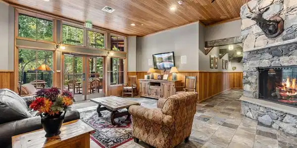 Image 3: A shared lounge; Vaulted wood ceilings and a floor-to-ceiling stone fireplace set the tone for cozy mountain evenings after a day on the slopes. Image 3: A shared lounge; Vaulted wood ceilings and a floor-to-ceiling stone fireplace set the tone for cozy mountain evenings after a day on the slopes.