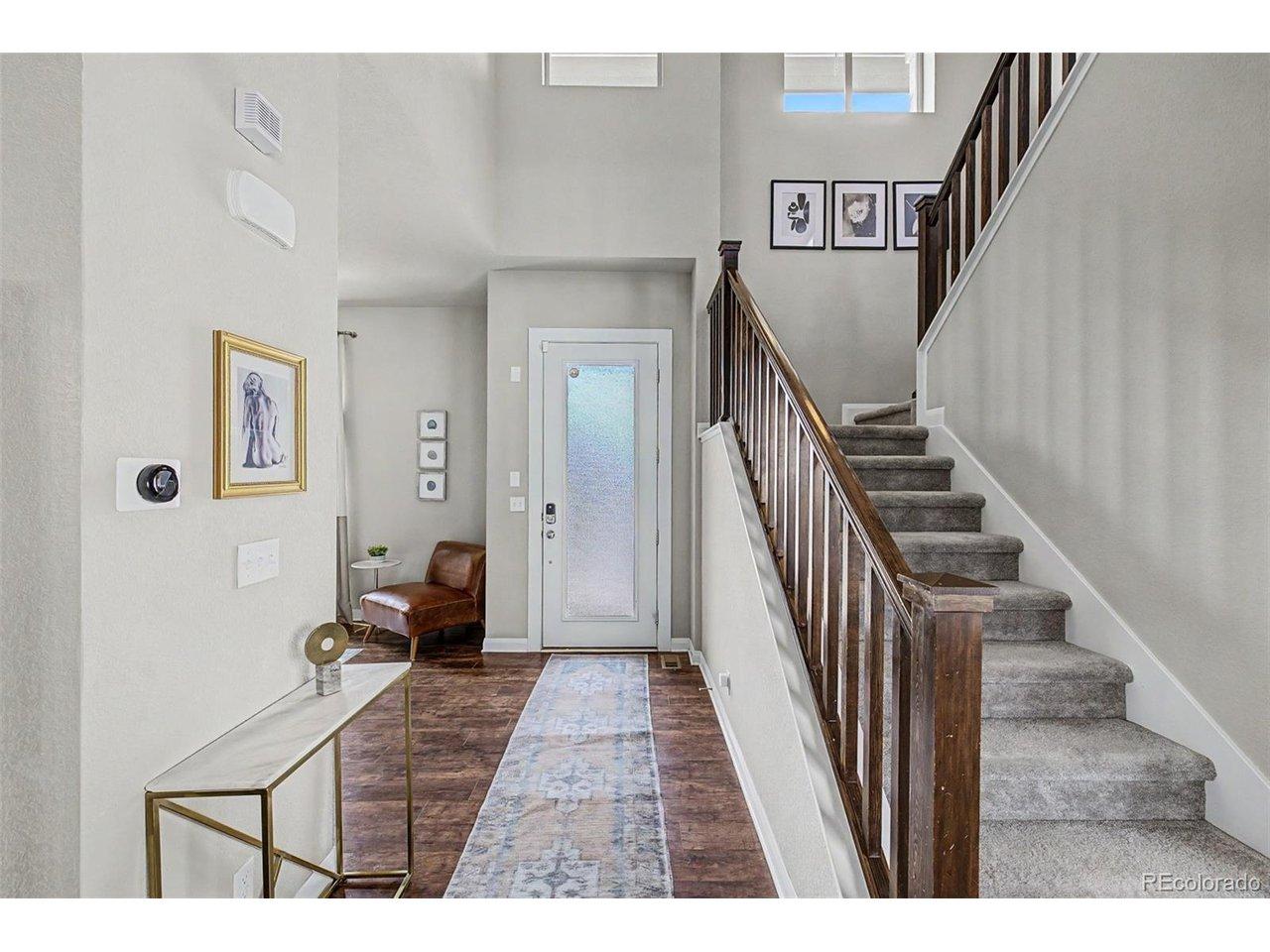 Image 4: Dramatic two-story entry foyer with rich hardwood-style flooring, elegant staircase with dark wood railing, runner rug, and smart home thermostat. Console table and curated art create an inviting first impression. Image 4: Dramatic two-story entry foyer with rich hardwood-style flooring, elegant staircase with dark wood railing, runner rug, and smart home thermostat. Console table and curated art create an inviting first impression.