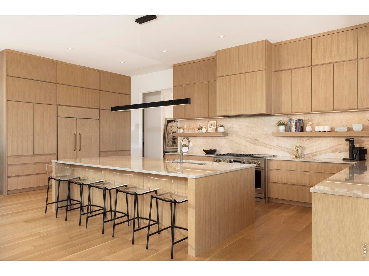Image 3: The chef's kitchen features a marble backsplash, floating shelves, and a large island with an undermount sink, complemented by paneled GE Monogram and Bosch appliances, including a 6-burner range.