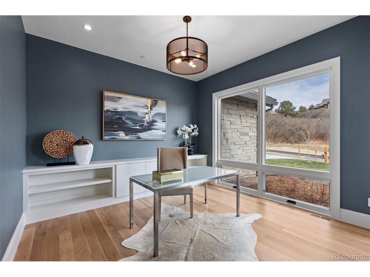 Image 4: Main level office with expansive windows, custom built-ins, and a clean, modern aesthetic.