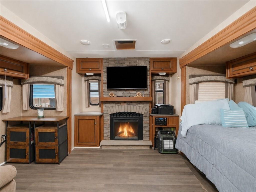 Image 4: Great Room, The great room for the Jaybird boasts a stone-clad fireplace with hearth, luxury-vinyl plank flooring, built-in cabinetry, recessed lighting, and multiple windows with blinds.