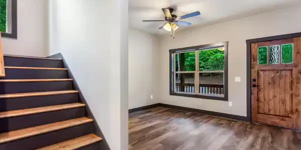 Image 4: Entry, Wood-finish flooring, natural wood entry door with glass panels, large picture window, ceiling fan with light fixture, and wood tread staircase