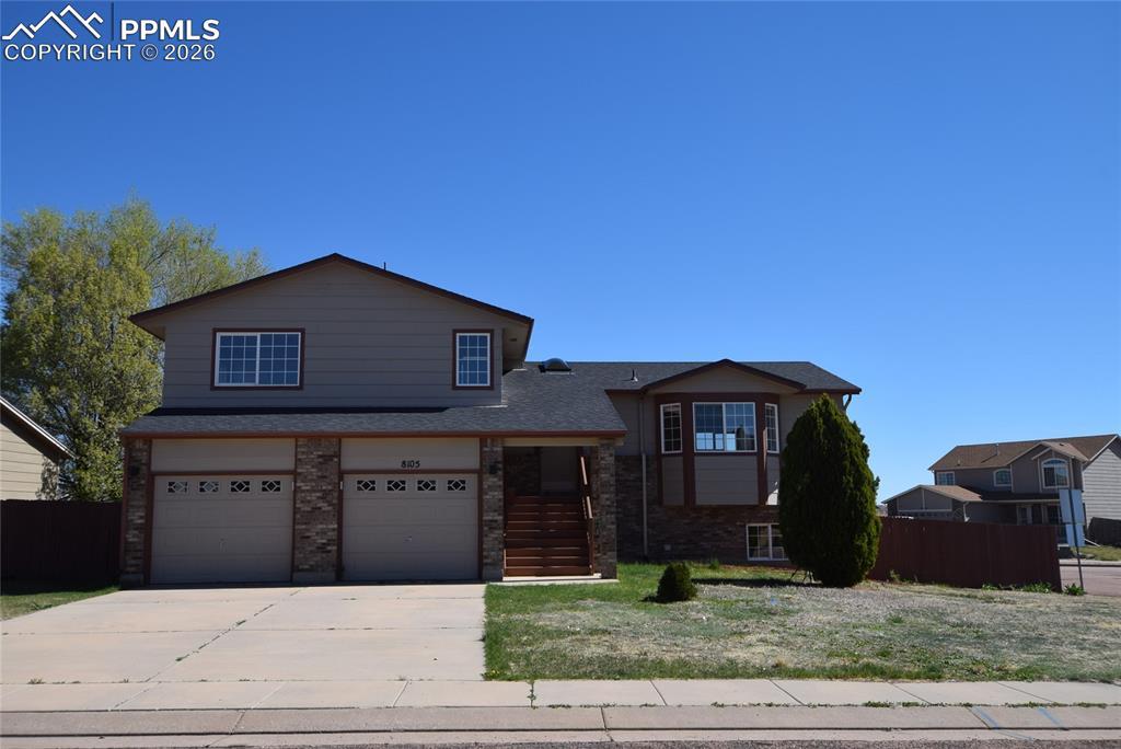 Image 1: Tri-level home featuring brick siding, a garage, and driveway