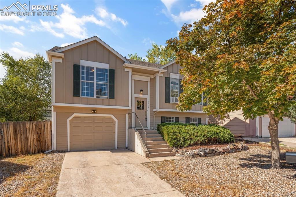 Image 1: Split foyer home with board and batten siding, concrete driveway, and a garage