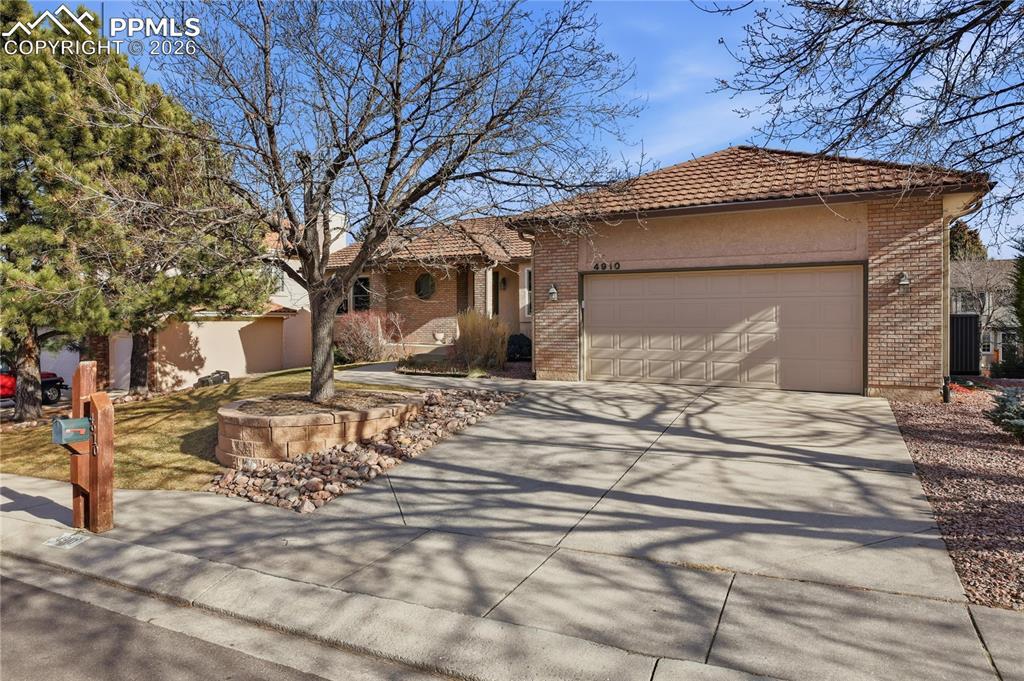 Image 3: Ranch-style home featuring driveway, a garage, a tile roof, and brick siding