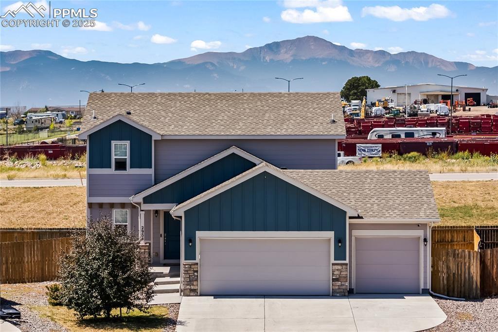 Image 2: View of front facade with roof with shingles, a mountain view, and board and batten siding