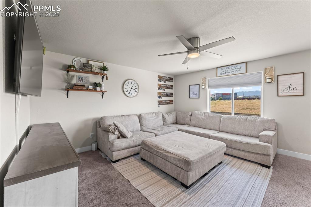 Image 3: Living area with carpet flooring, a textured ceiling, and ceiling fan