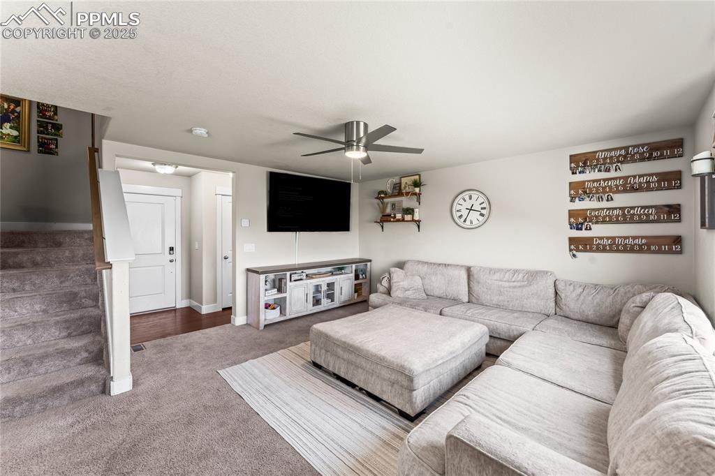 Image 4: Carpeted living room with stairway and a ceiling fan