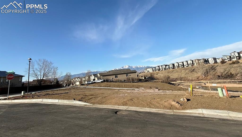 Image 1: View of asphalt street with curbs, a mountain view, and street lights