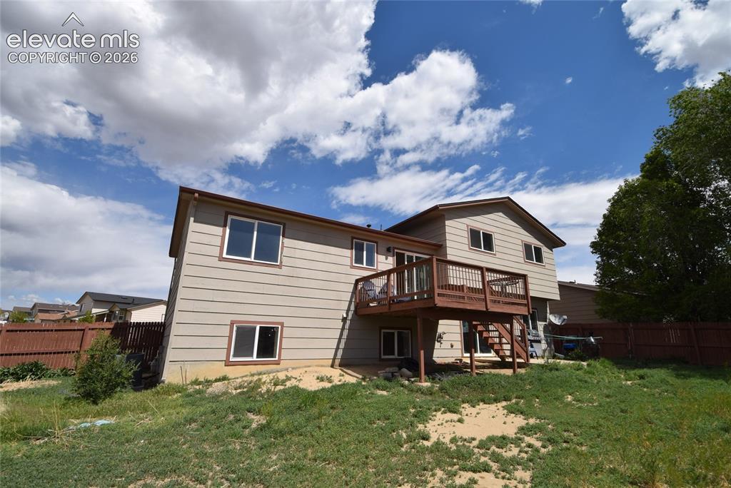 Image 4: Expansive exterior featuring a wood-finish multi-level deck, beige siding, white window frames, brown roof trim, and a fenced perimeter
