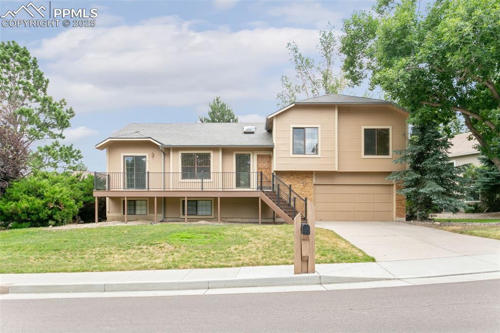 Image 2: Split level home featuring concrete driveway, a front lawn, an attached garage, and stairway