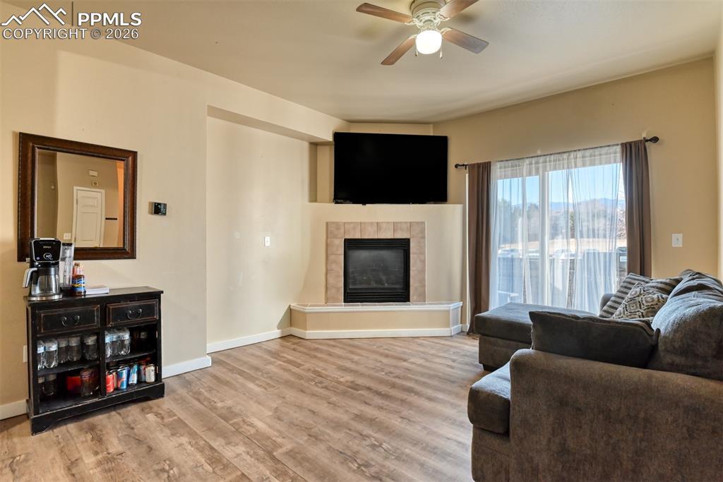Image 3: Living room featuring a ceiling fan, light wood-style floors, and a tiled fireplace
