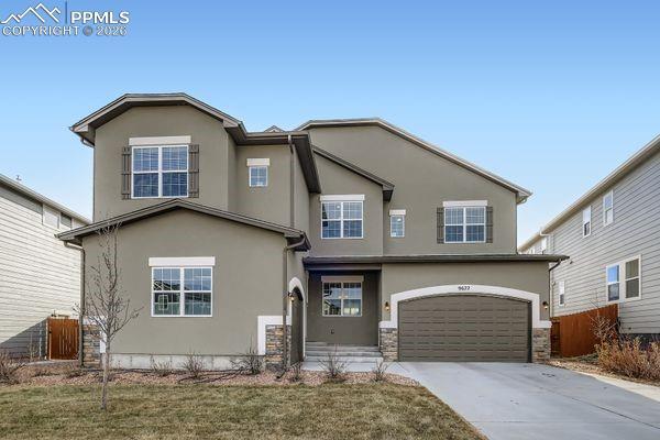 Image 1: View of front facade with stucco siding, driveway, and an attached garage