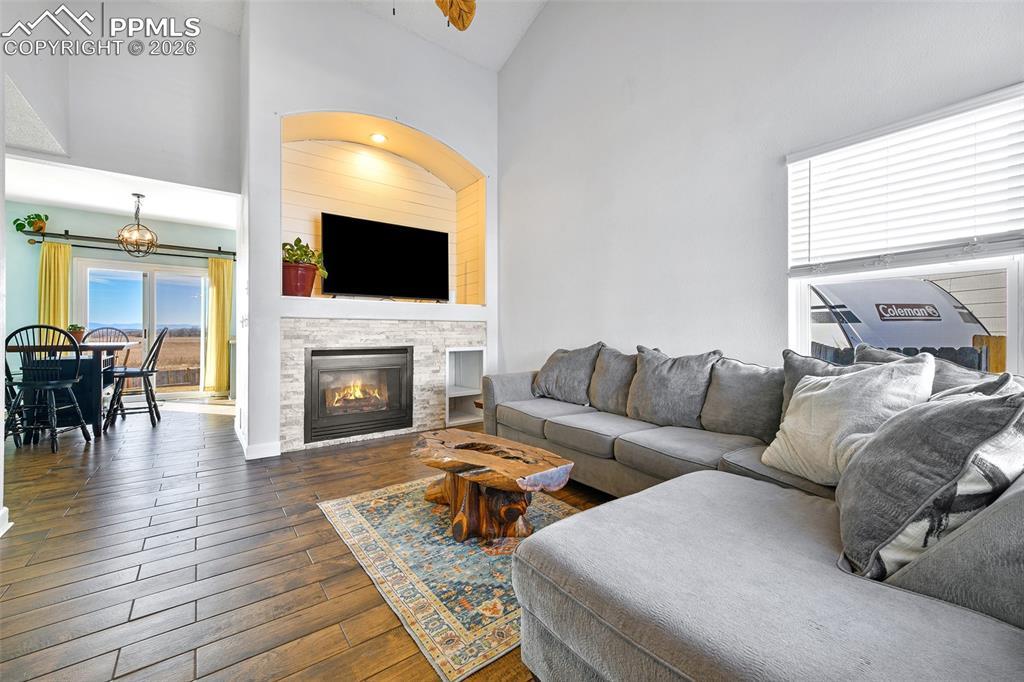 Image 3: Living area featuring dark wood finished floors, high vaulted ceiling, and a stone fireplace