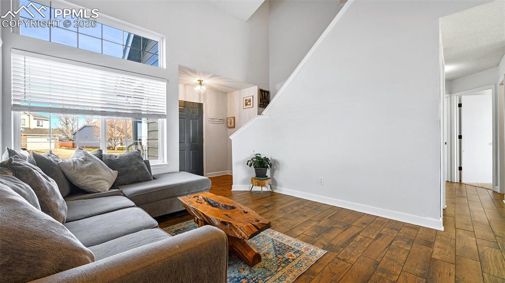 Image 4: Living room featuring dark wood-style floors, a high ceiling, and stairs
