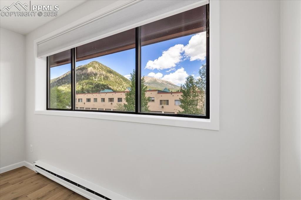 Image 3: Unfurnished room with baseboard heating, wood finished floors, and a mountain view