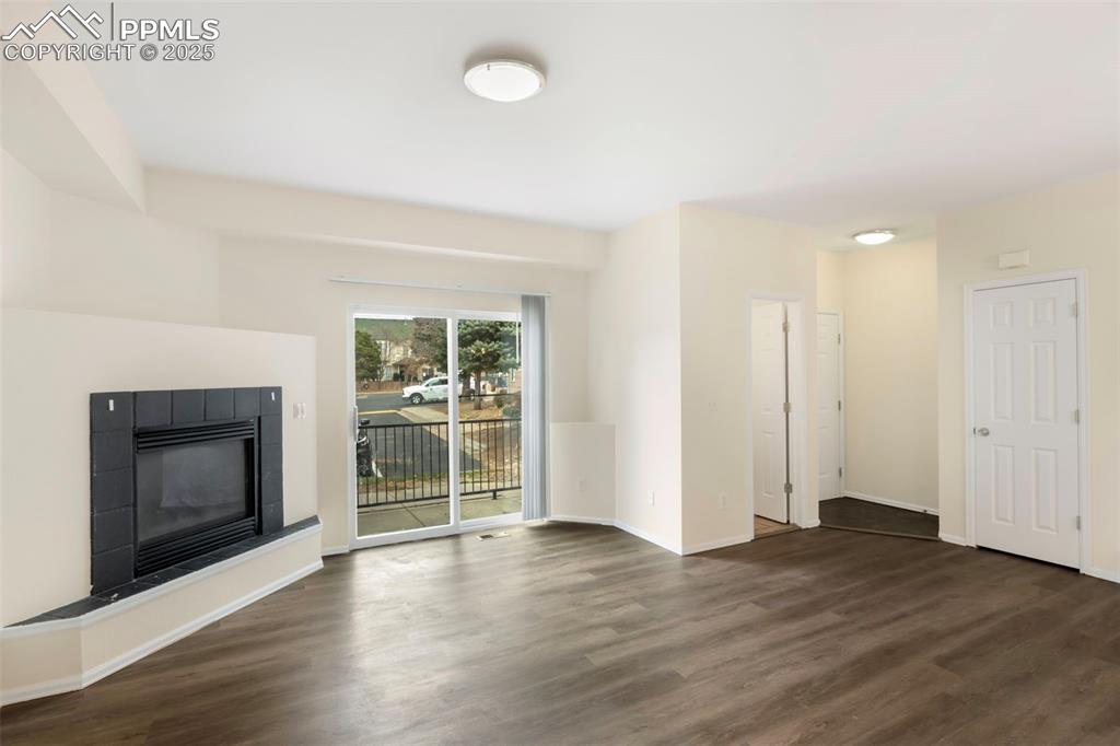 Image 4: Unfurnished living room with a tile fireplace and dark wood-style floors