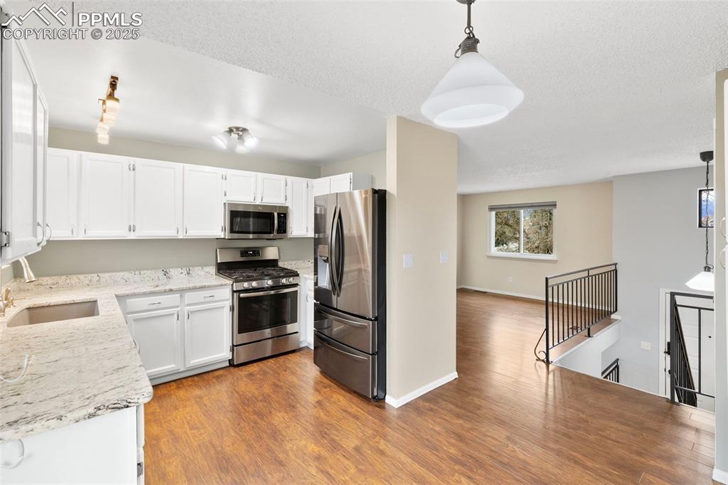 Image 4: Granite countertops, stainless steel appliances, engineered hardwood floors.