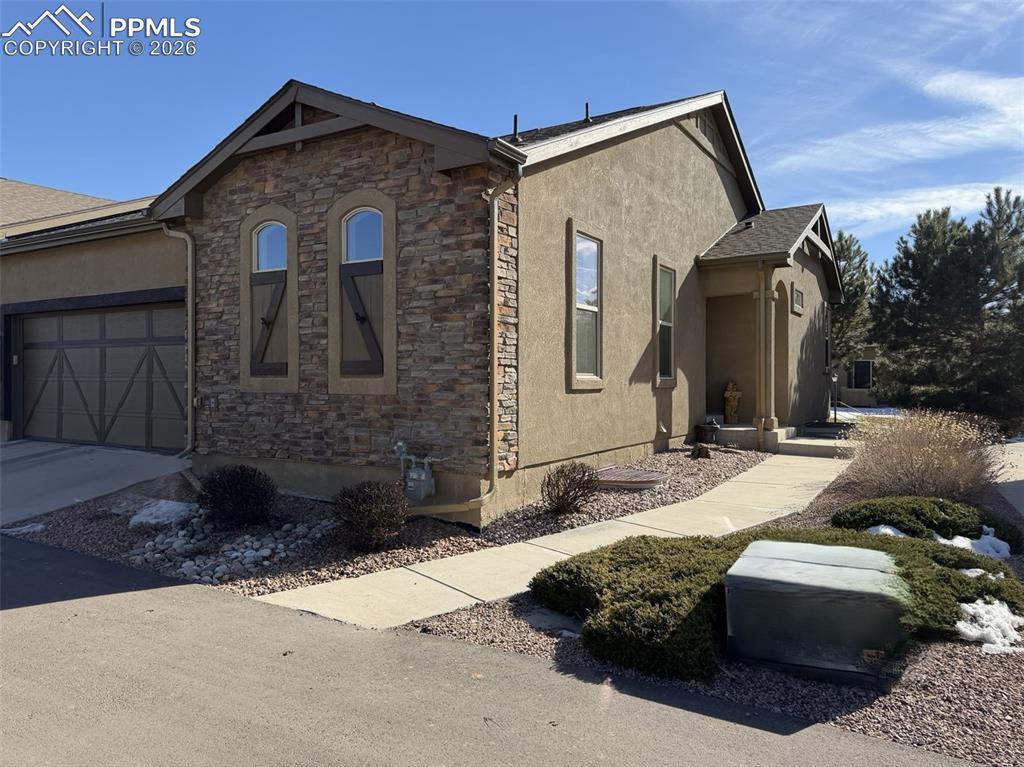 Image 1: View of front of property featuring stucco siding, stone siding, concrete driveway, and an attached garage